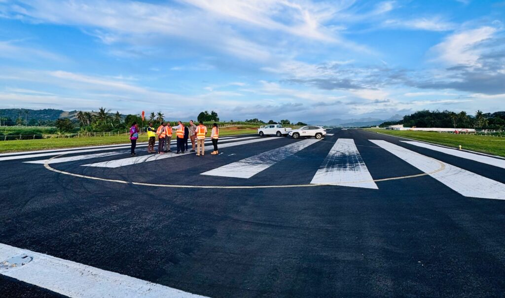 : Members of the project team walking along the runway at Labasa Airport during a technical site assessment.